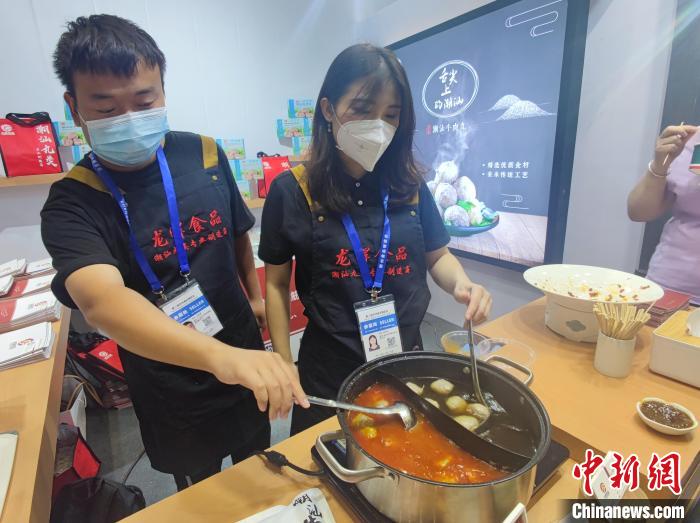 图为李焙玉(右)与同事烹煮牛肉丸供市民免费品尝。　阚力 摄